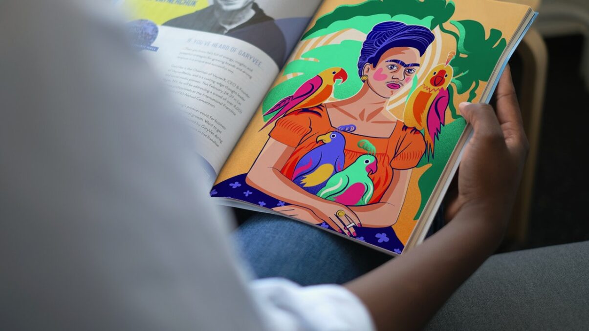 A mockup photo presenting the illustration dedicated to Frida Kahlo and her parrots, mocked up on a magazine read by a woman