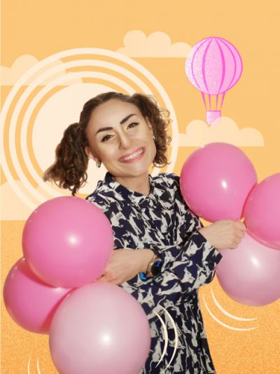 Girl holding balloons in her hands. The character is depicted on a sunny background. A hot air balloon can be seen on the sky.