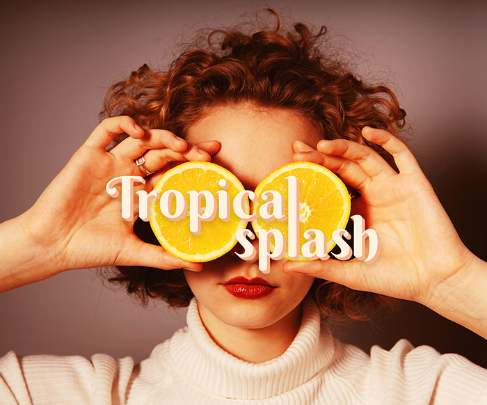 Tropical splash secondary logo on top of a photo featuring a girl holding two slices of oranges on top of her eyes