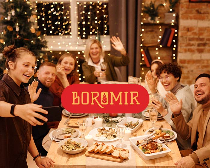 Boromir logotype placed on top of a photo featuring a group of people taking a selfie during a dinner