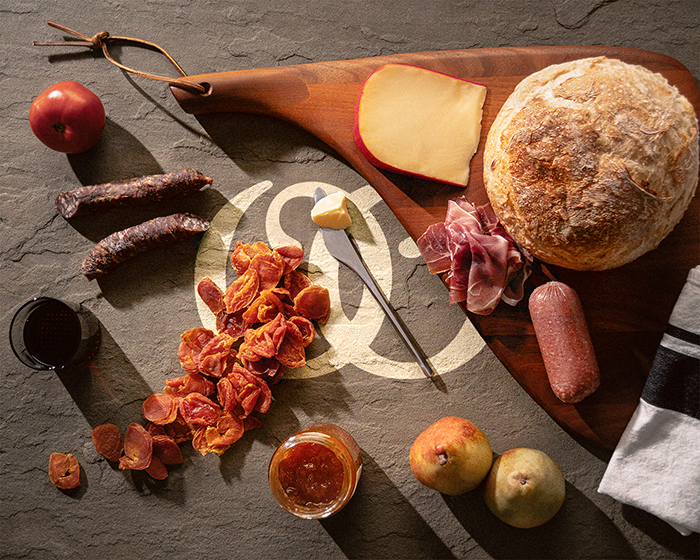 Rebranding Olympia mockup logo mark - on a table there are fruits, sausages, cheese and bread on top of the logo - passion project by ©Loredana Codau