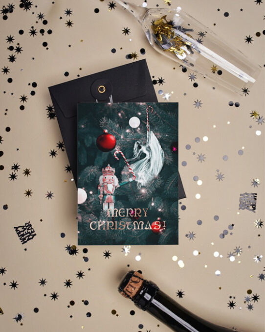 Christmas card mockup depicting a Christmas love story presented on a Christmas card, placed on a flat surface covered with confetti between a Champaign glass and a Champaign bottle
