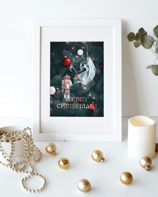 Christmas card mockup depicting a Christmas love story presented on a white frame places on the wall. Next to it there are Christmas tree ornaments, a candle, and an eucalyptus branch
