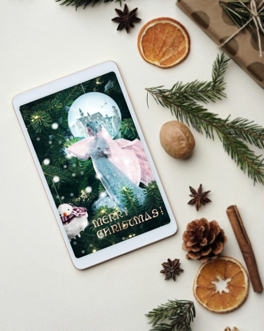 Christmas card mockup depicting The frozen kingdom presented on a tablet, placed on a flat surface between dried orange slices, Christmas tree branches, vanilla sticks, presents and anise stars