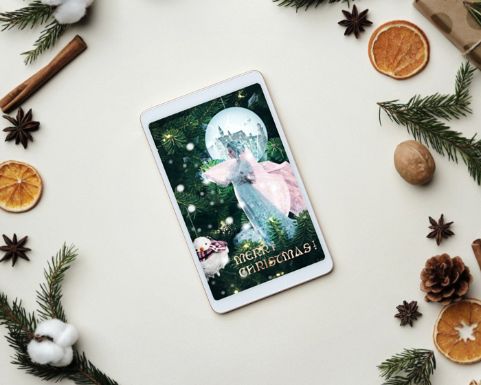 Christmas card mockup depicting The frozen kingdom presented on a tablet, placed on a flat surface between dried orange slices, Christmas tree branches, vanilla sticks, presents and anise stars